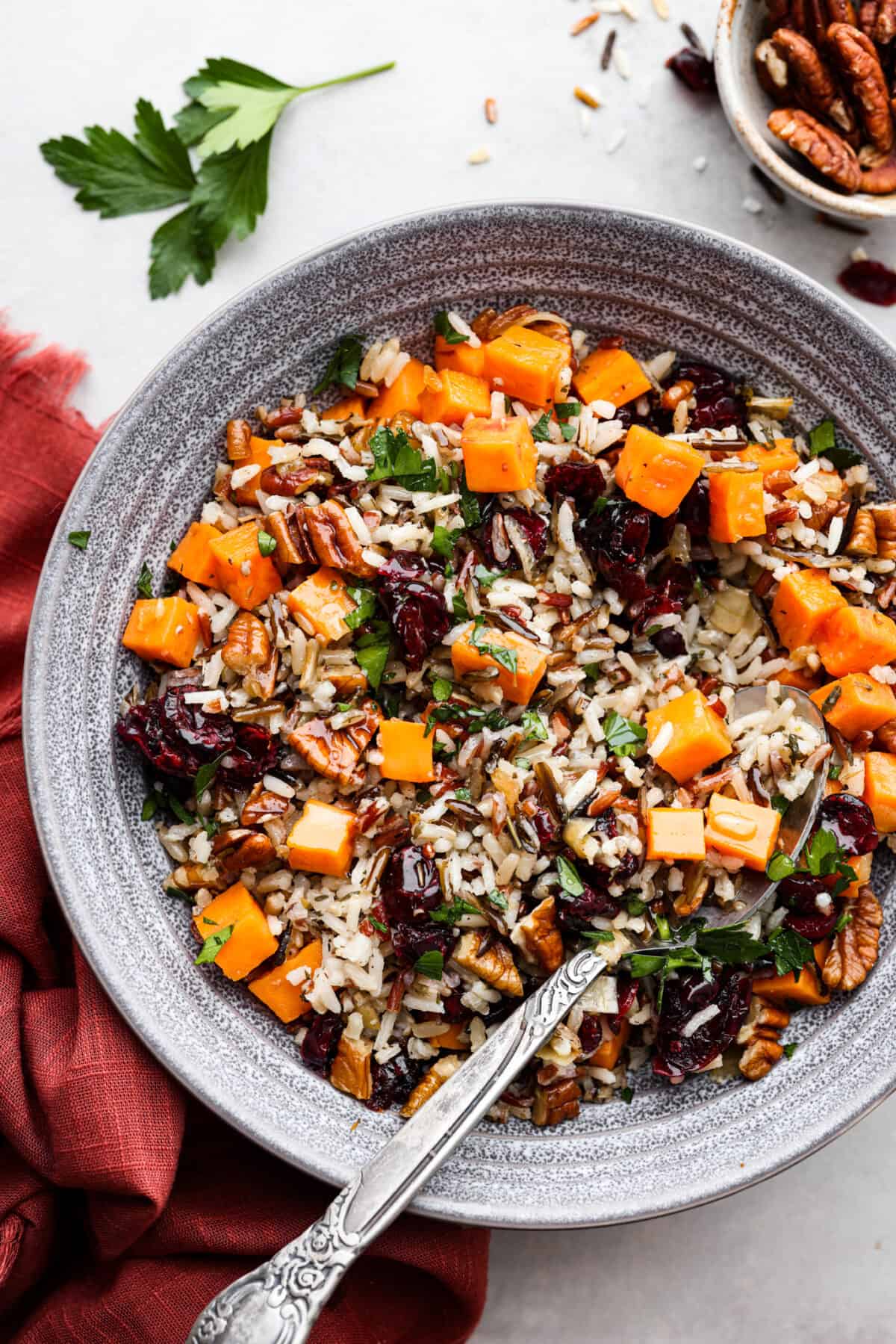 Top view of cranberry pecan sweet potato wild rice pilaf in a gray bowl with a in the bowl spoon. 