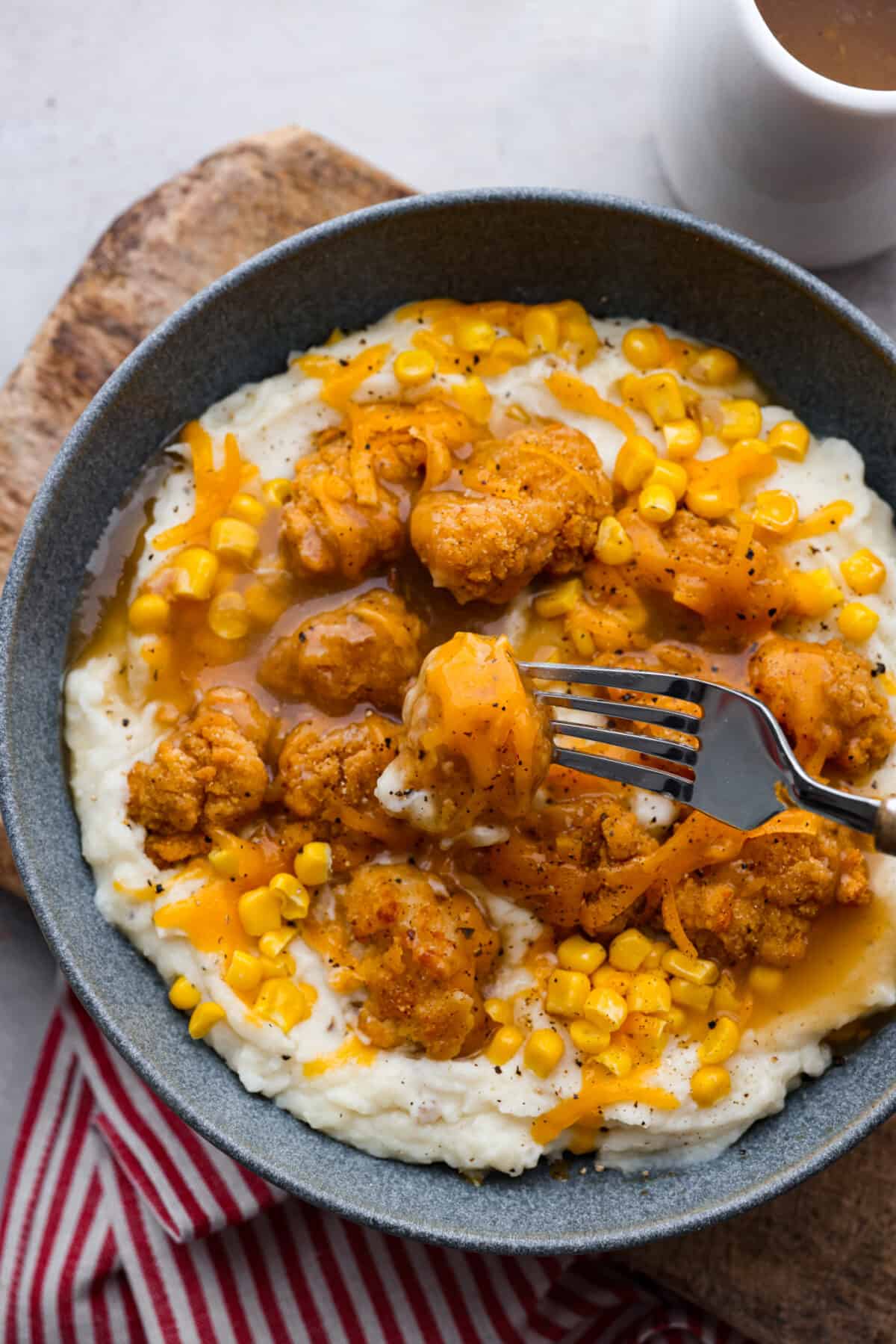 Crispy chicken, mashed potatoes and gravy and corn served in a gray bowl.