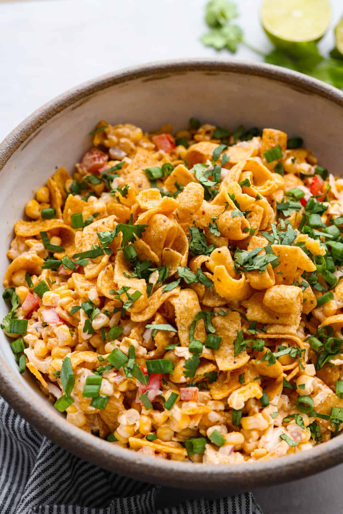 Close view of frito corn salad in a large bowl garnished with cilantro and green onions.