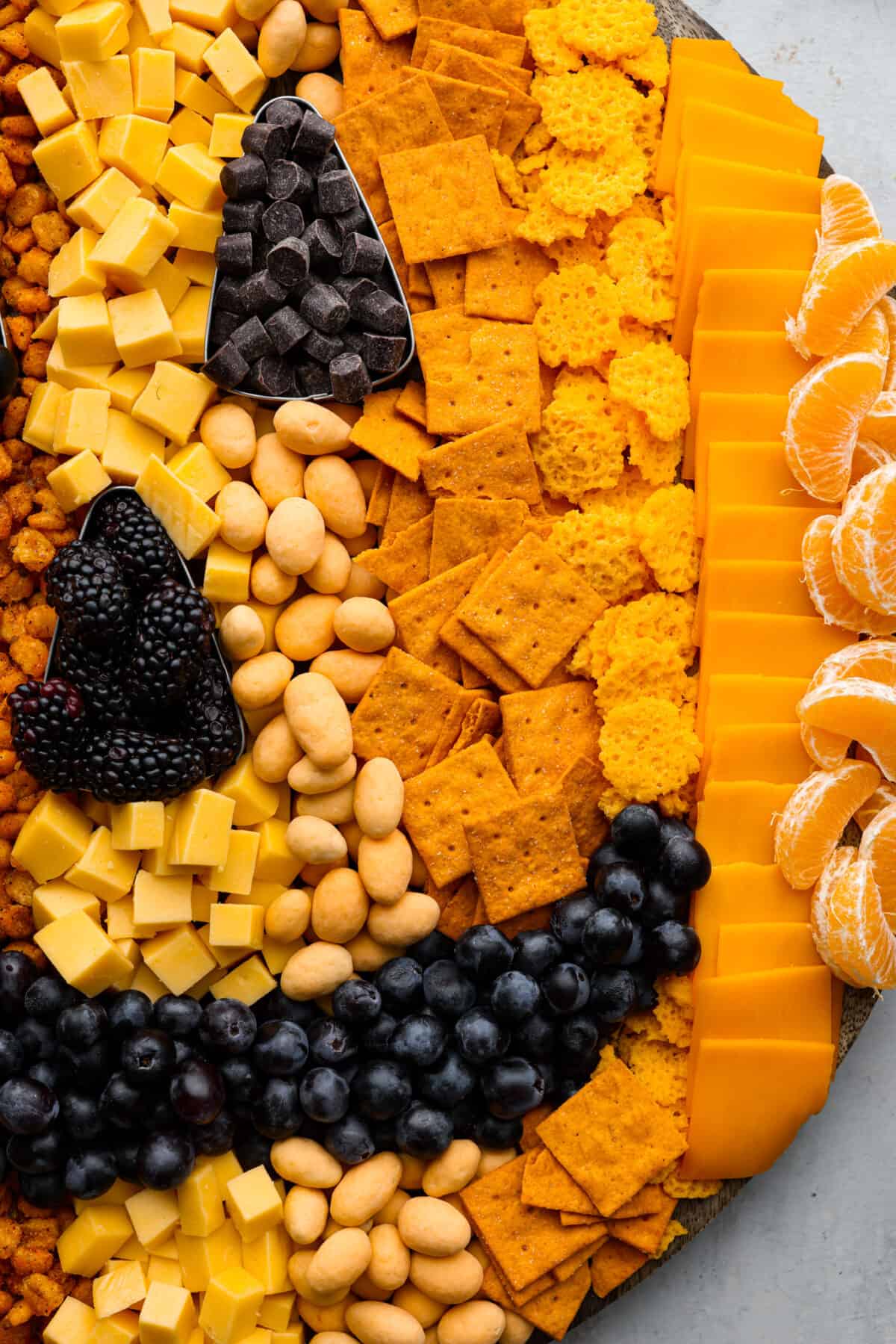 Close view of crackers, cheese, fruit, and candy on the pumpkin charcuterie board.