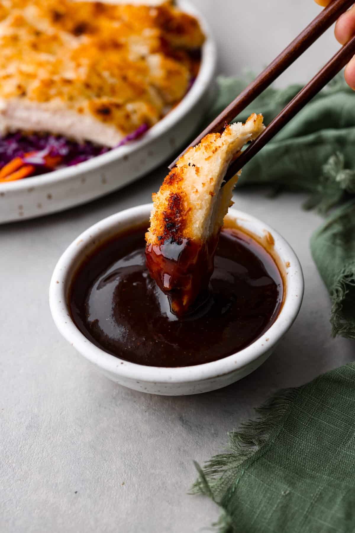 Dipping a piece of breaded chicken in the sauce.