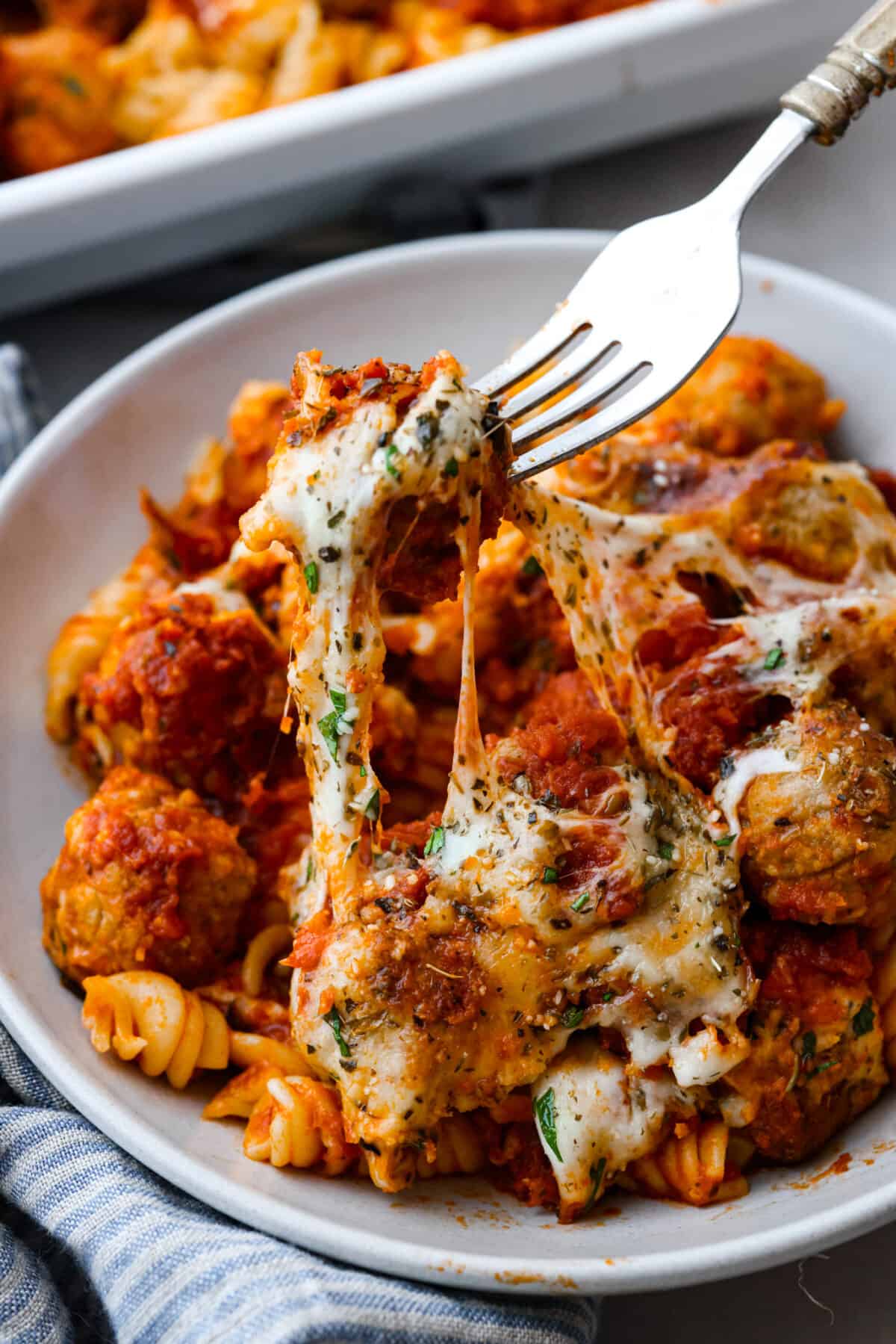 Picking up a cheesy meatball with a fork.
