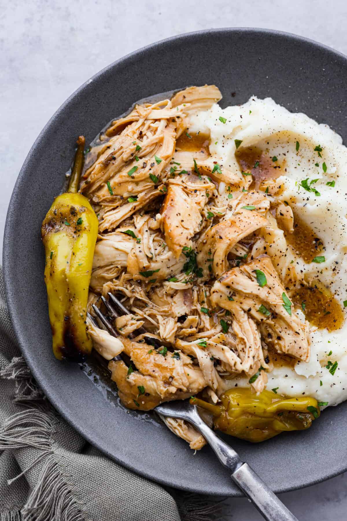 Shredded chicken served on a gray plate with mashed potatoes.