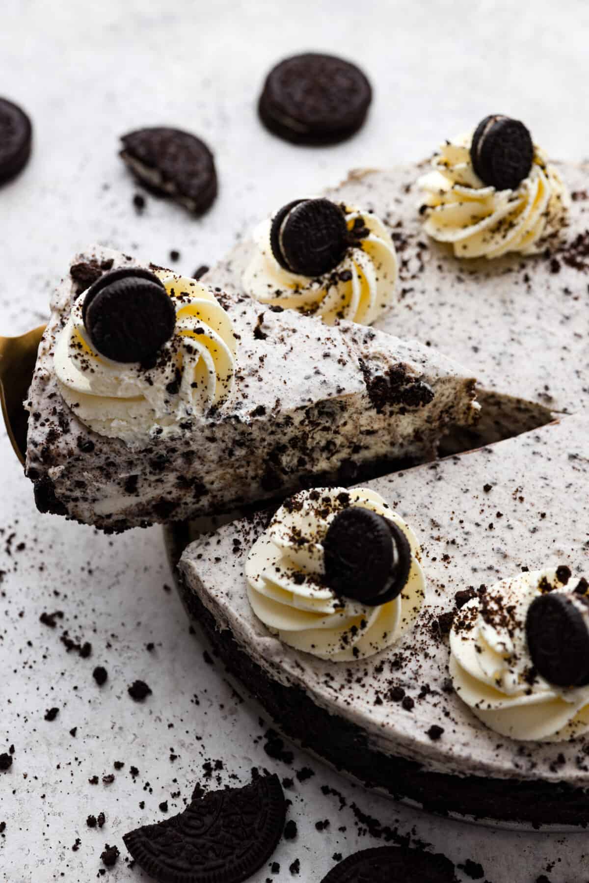 One slice cut out of a whole no bake Oreo cheesecake.