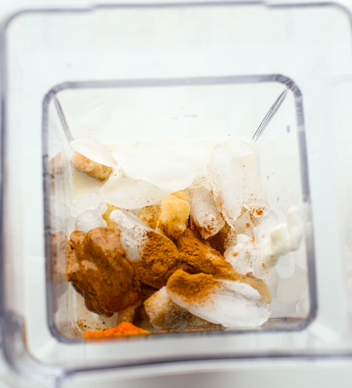 Ice cubes, pumpkin pie spice, pumpkin puree, frozen bananas and almond butter in a blender.