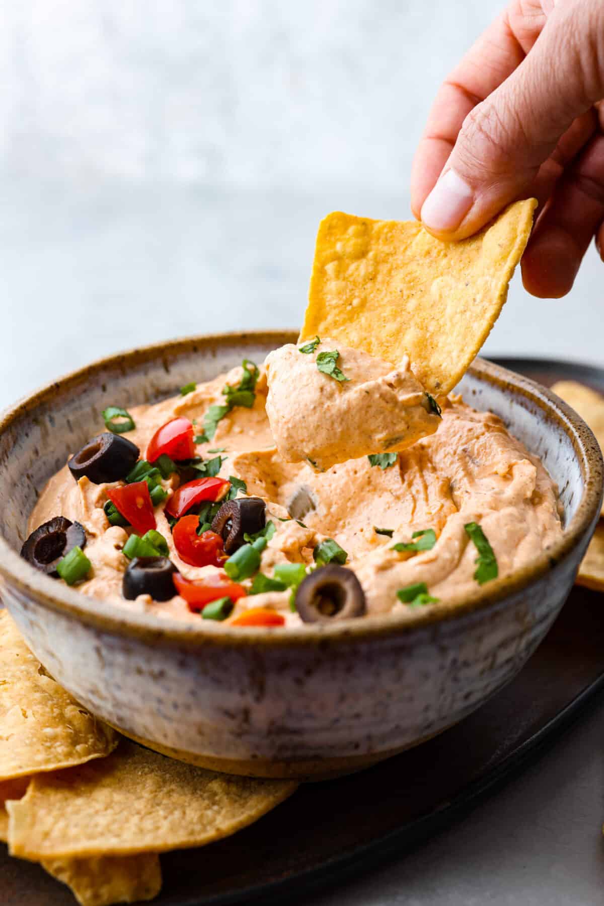 Dipping a tortilla chip into the dip.