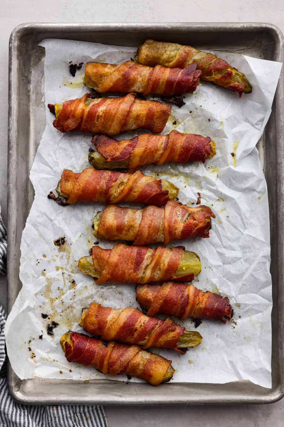 Bacon wrapped pickles on a baking sheet.