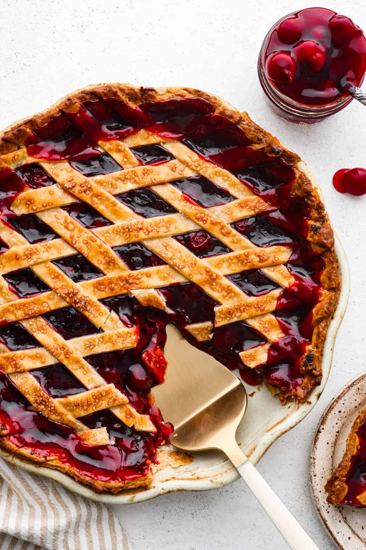 Top-down view of a cherry pie with a slice cut out of it.