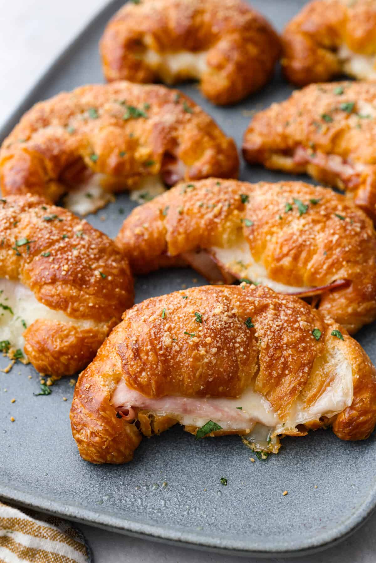 Close view of ham and cheese croissants on a blue platter.