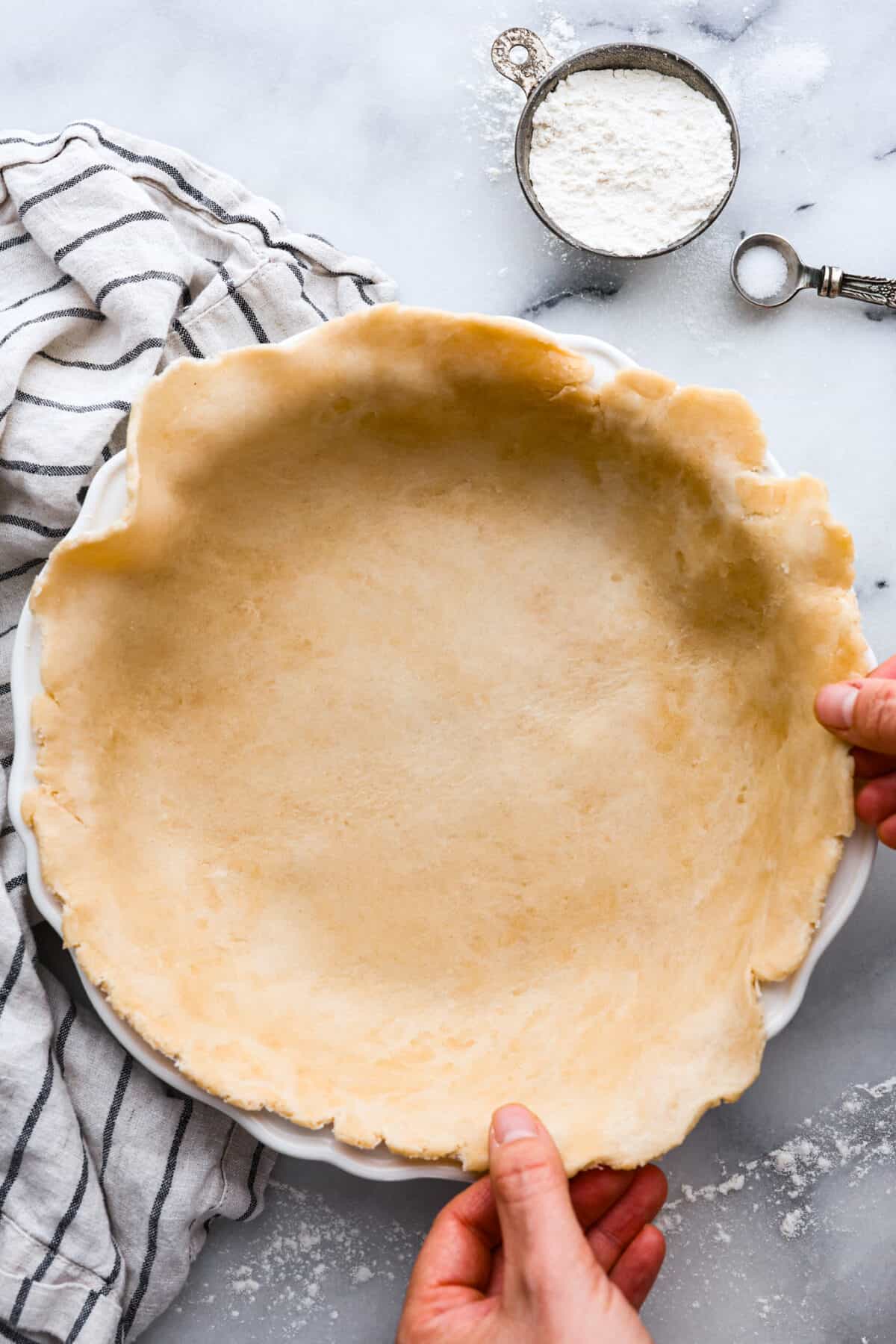 Placing a homemade, unbaked crust in a pie pan.