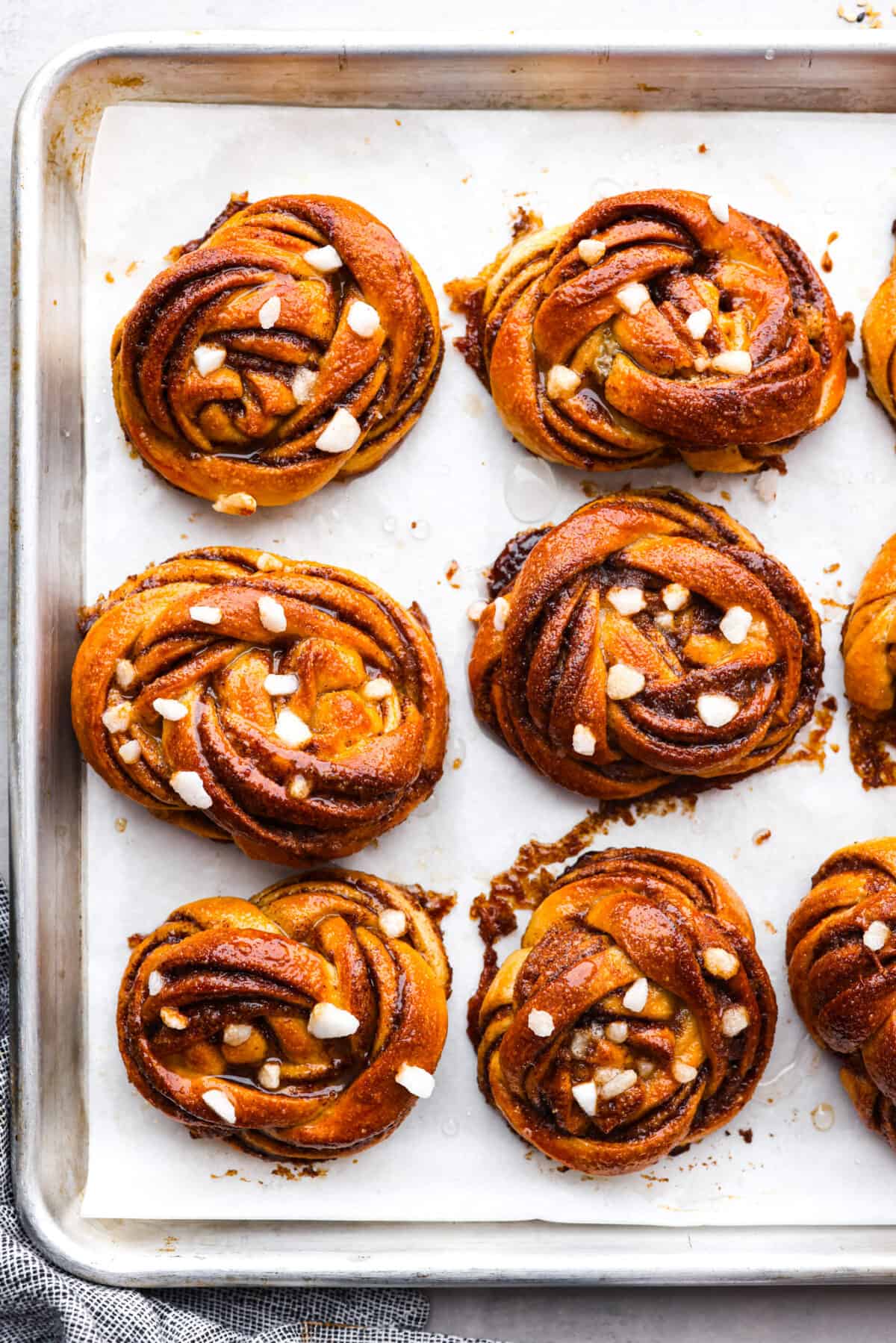Kanelbullar on a baking sheet lined with parchment paper.