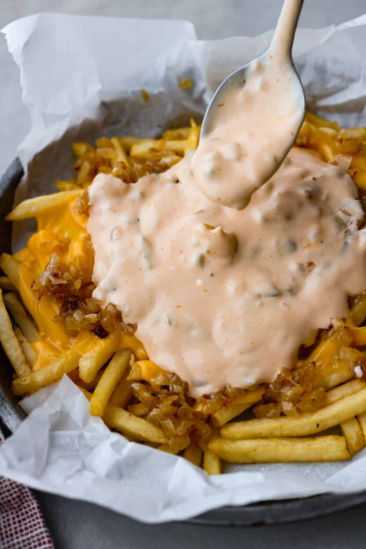 Spooning the zesty sauce over the animal fries.
