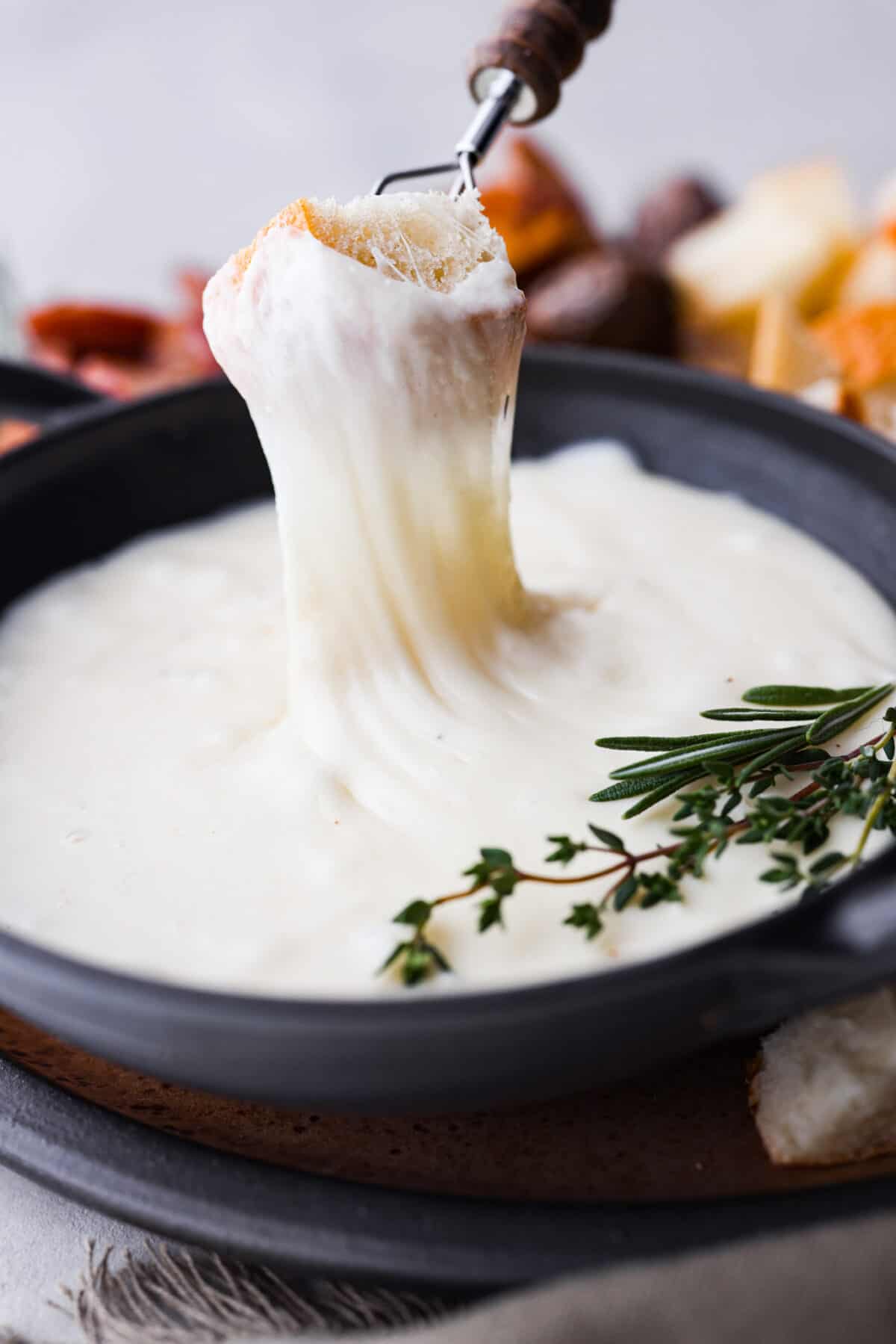 Dipping a piece of bread in the fondue, the cheese stretching as it’s lifted up.