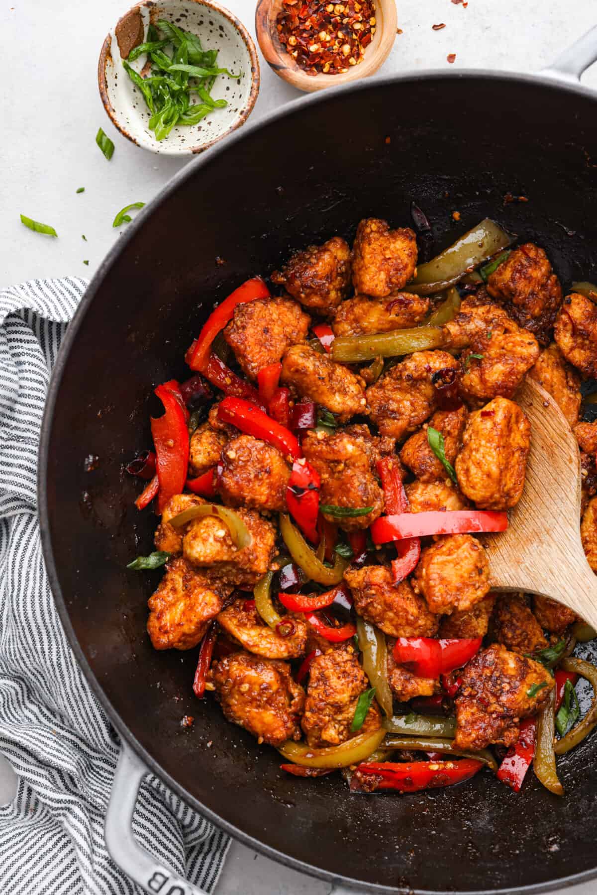 Cooked kung pao chicken with bell peppers in a black wok.
