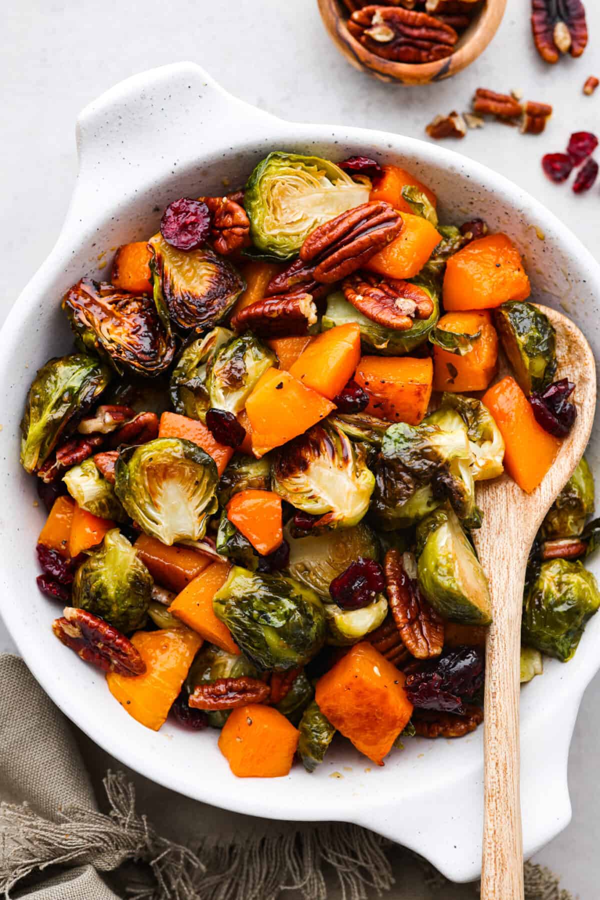 Squash, brussels sprouts, and pecans served in a white baking dish.