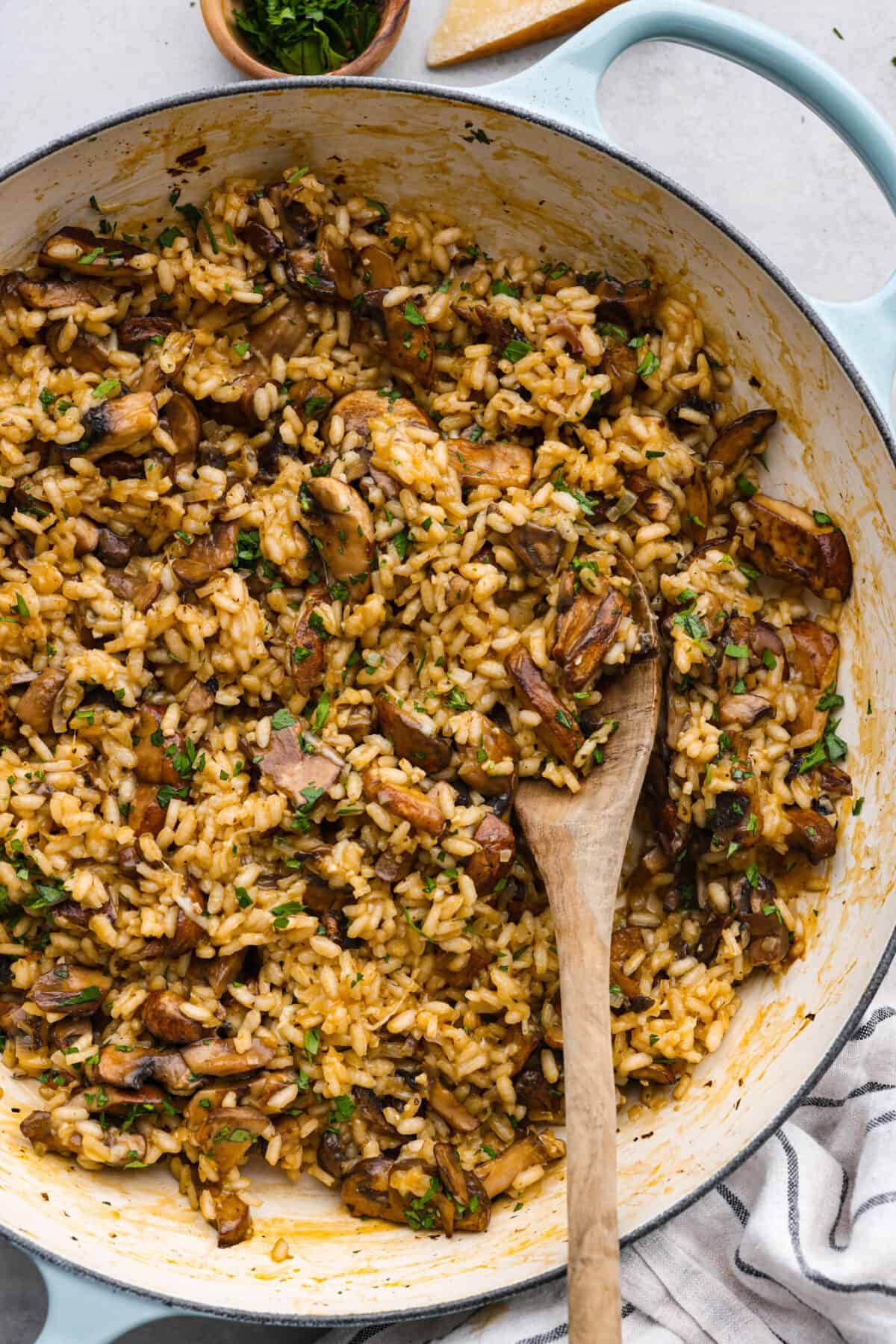 Top view of mushroom risotto in a blue and white frying pan.