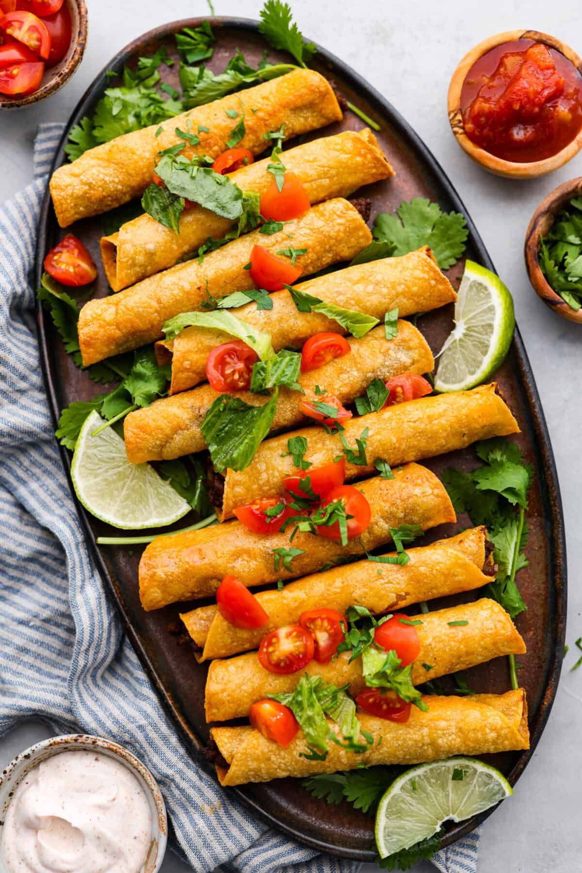 Beef taquitos on a black serving dish.