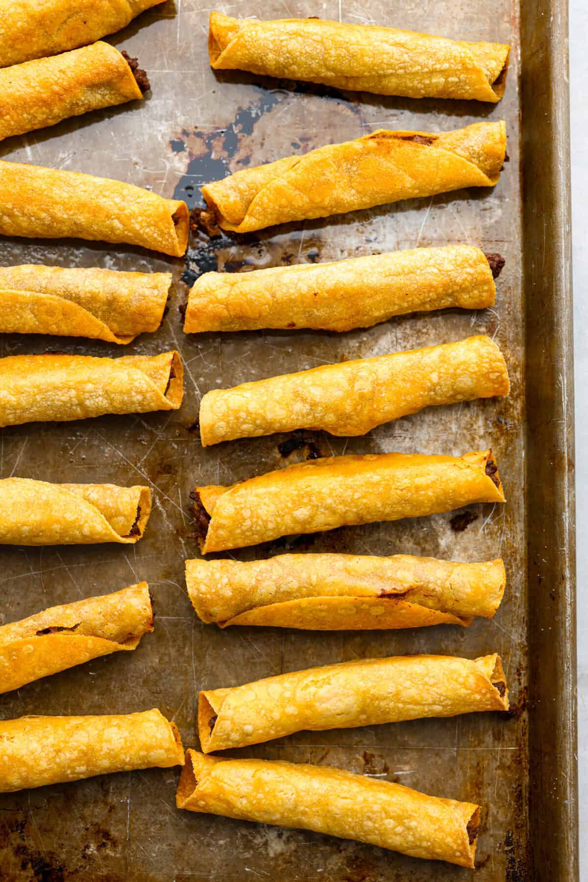Baked beef taquitos on a baking sheet.