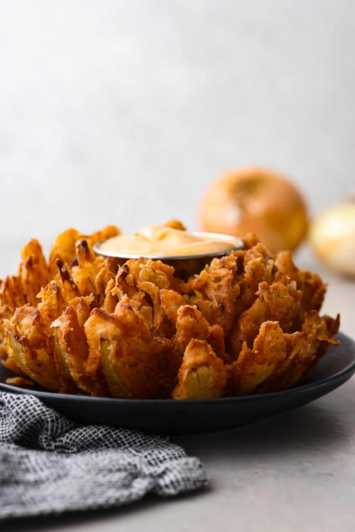 A bloomin onion served with a creamy dipping sauce.