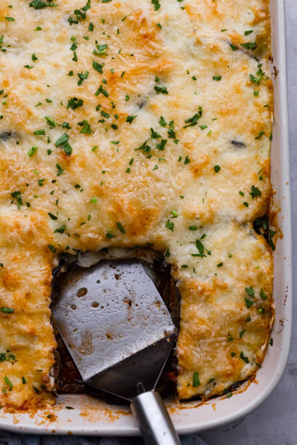 Top-down view of moussaka in a baking dish with a slice taken out of it.