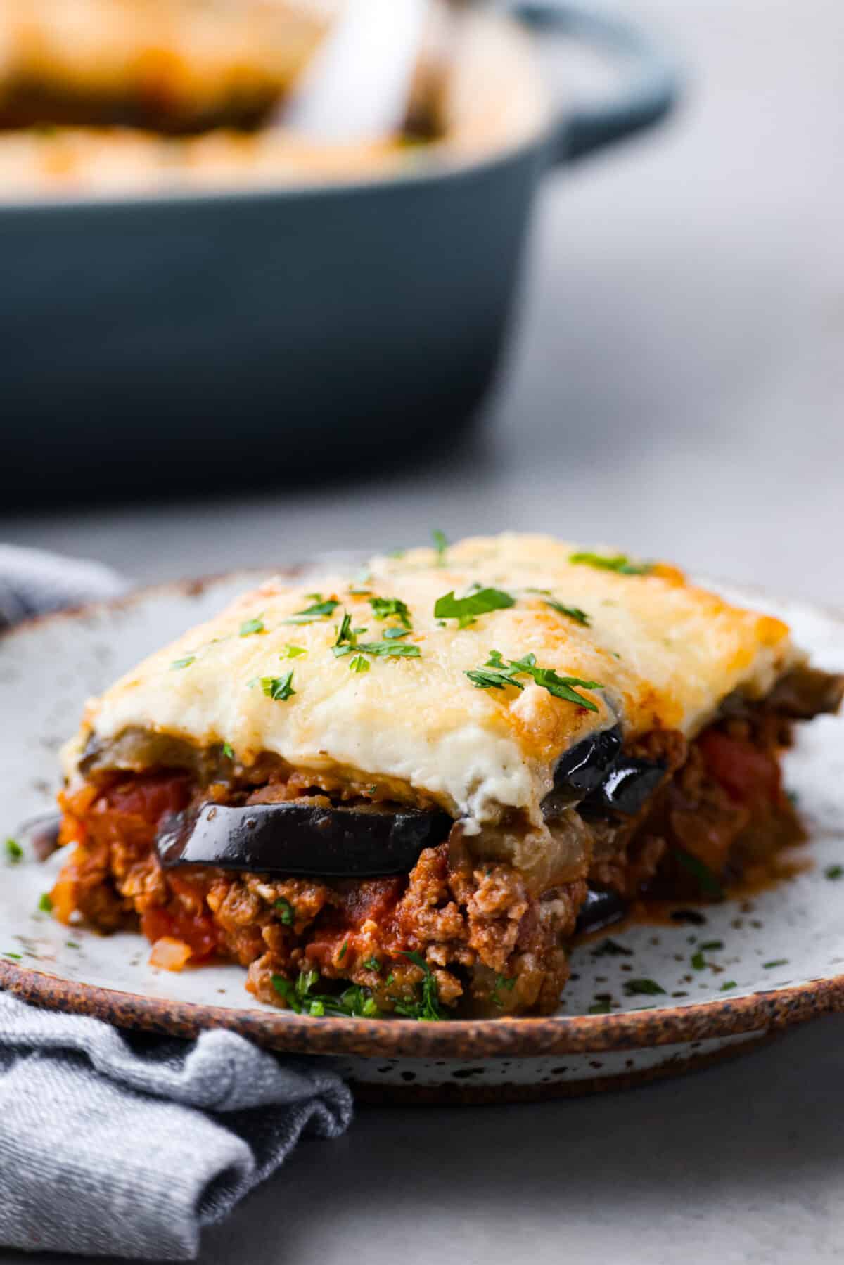 A slice of moussaka on a stoneware plate.
