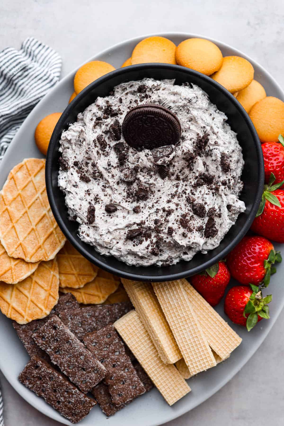 Cookies and cream dip served with a variety of wafers, cookies, waffle cone pieces, strawberries, and Nilla wafers.