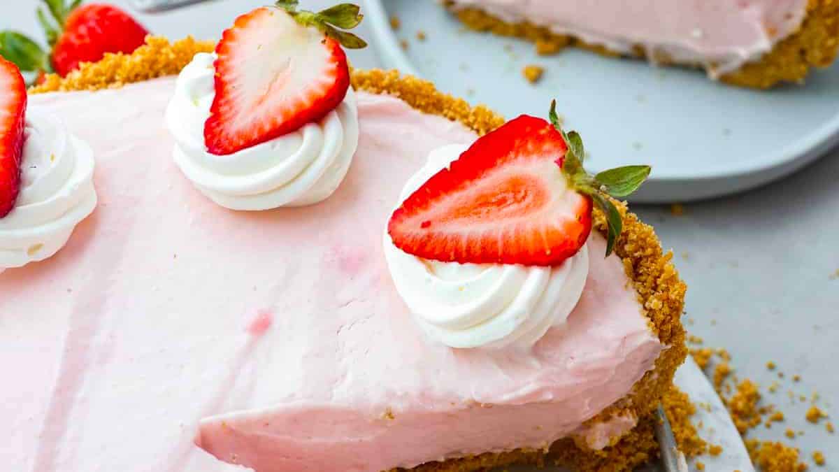 A photo of pink cheesecake with sliced strawberries on top. 
