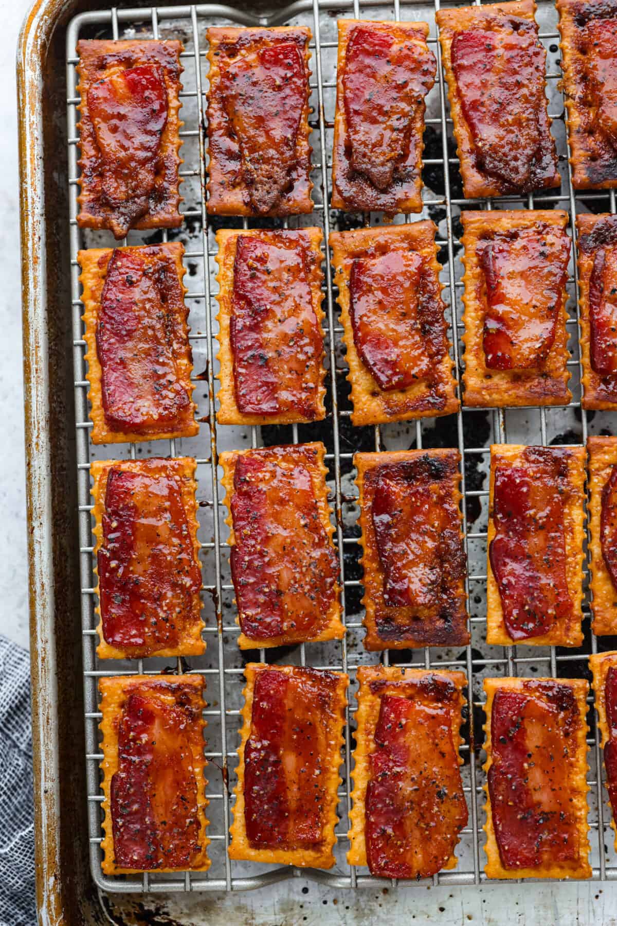 Close view of baked bacon crackers on a baking sheet pan lined with a wire rack.