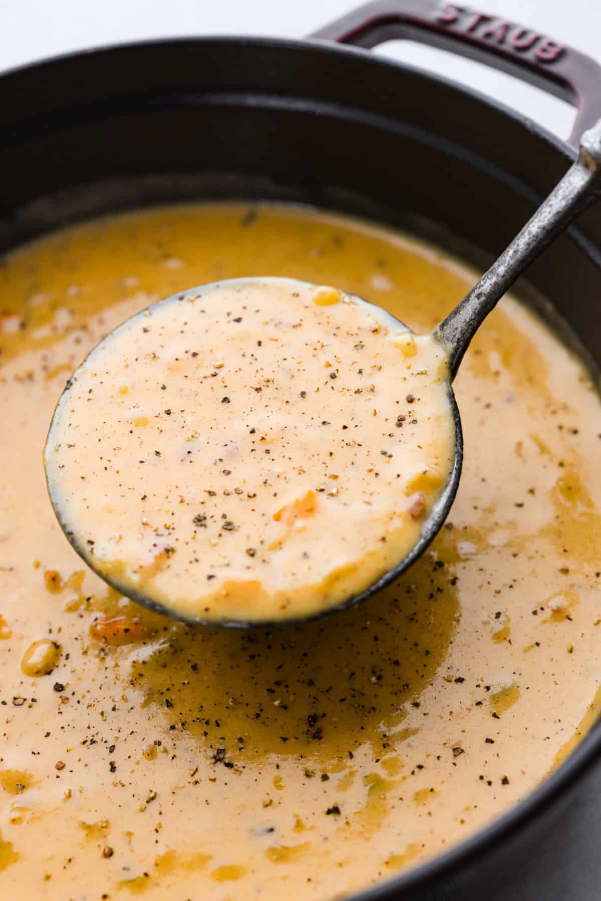 Beer cheese soup being served with a ladle.