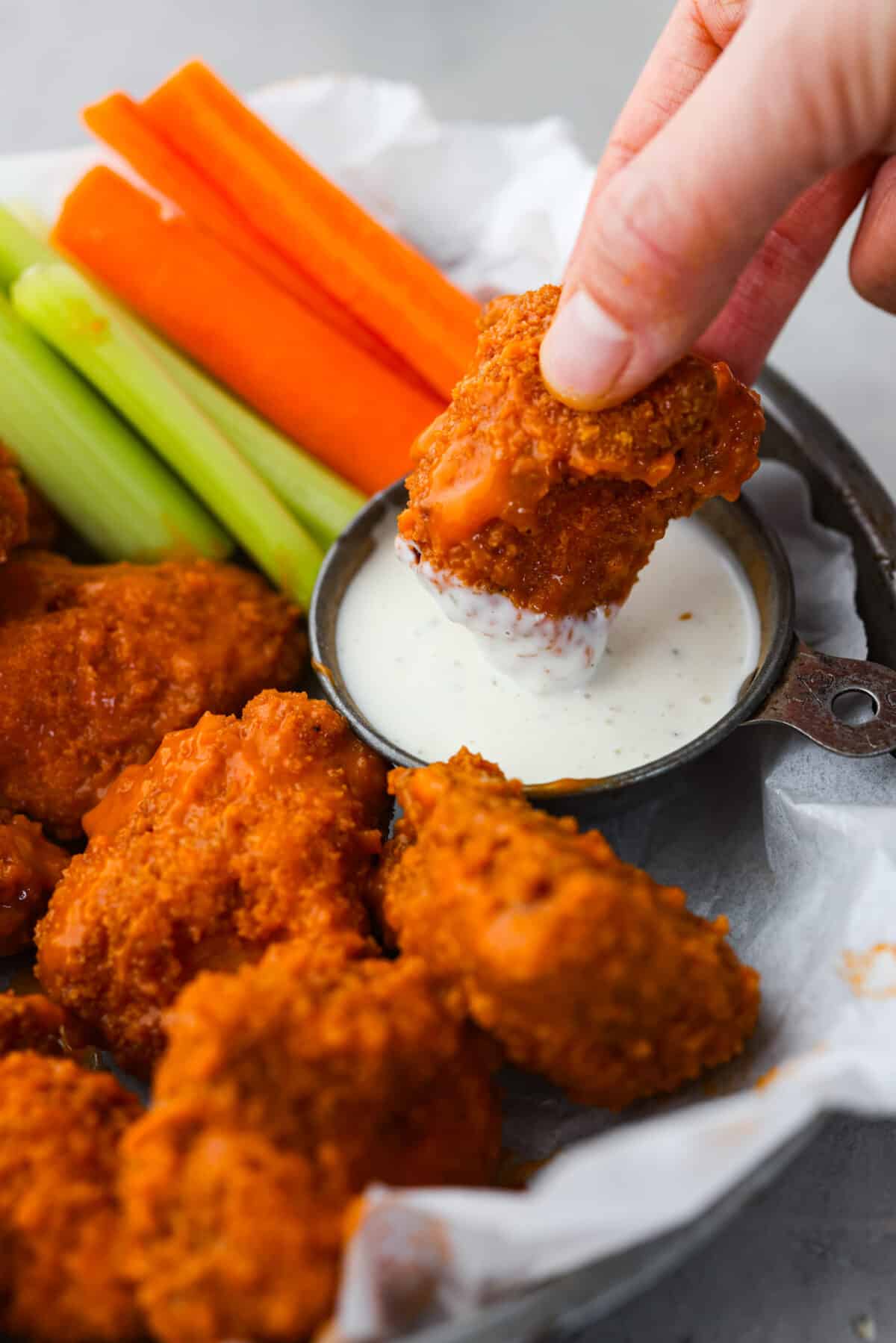 Dipping a buffalo wing into ranch dressing.