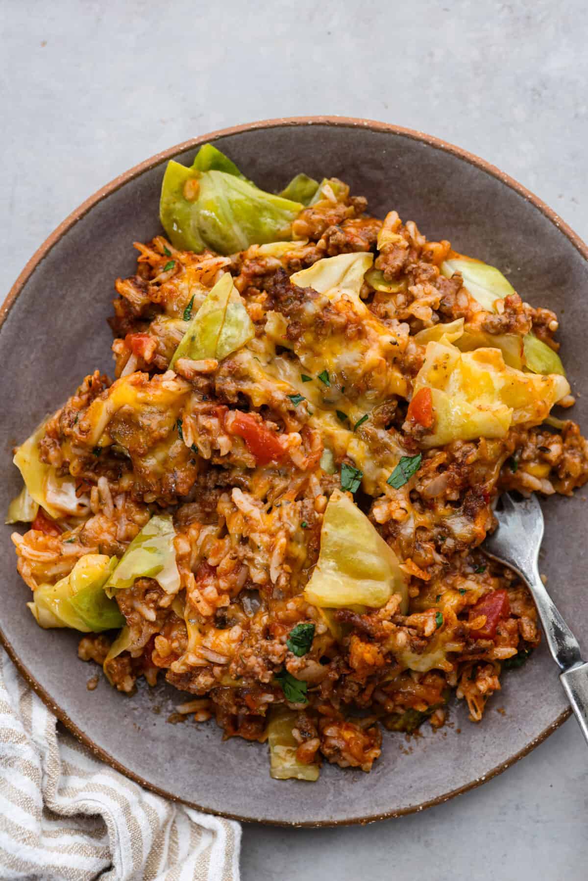 Top view of cabbage roll casserole on a brown plate with a fork.