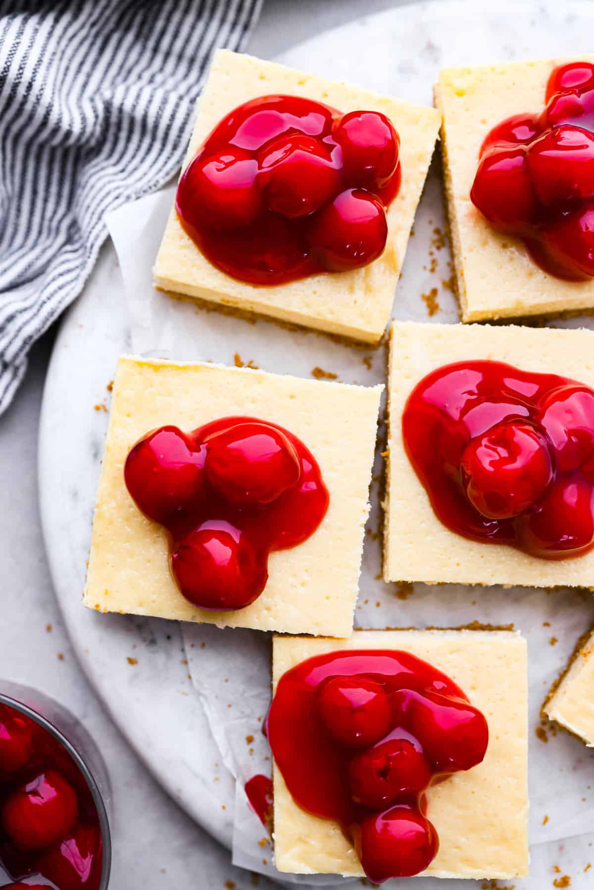 These Cherry Cheesecake Bars are the perfect make-ahead dessert for any occasion! Creamy cheesecake sits atop a homemade graham cracker crust, and is finished off with a generous helping of cherries. Top-down view of sliced cherry cheesecake bars.