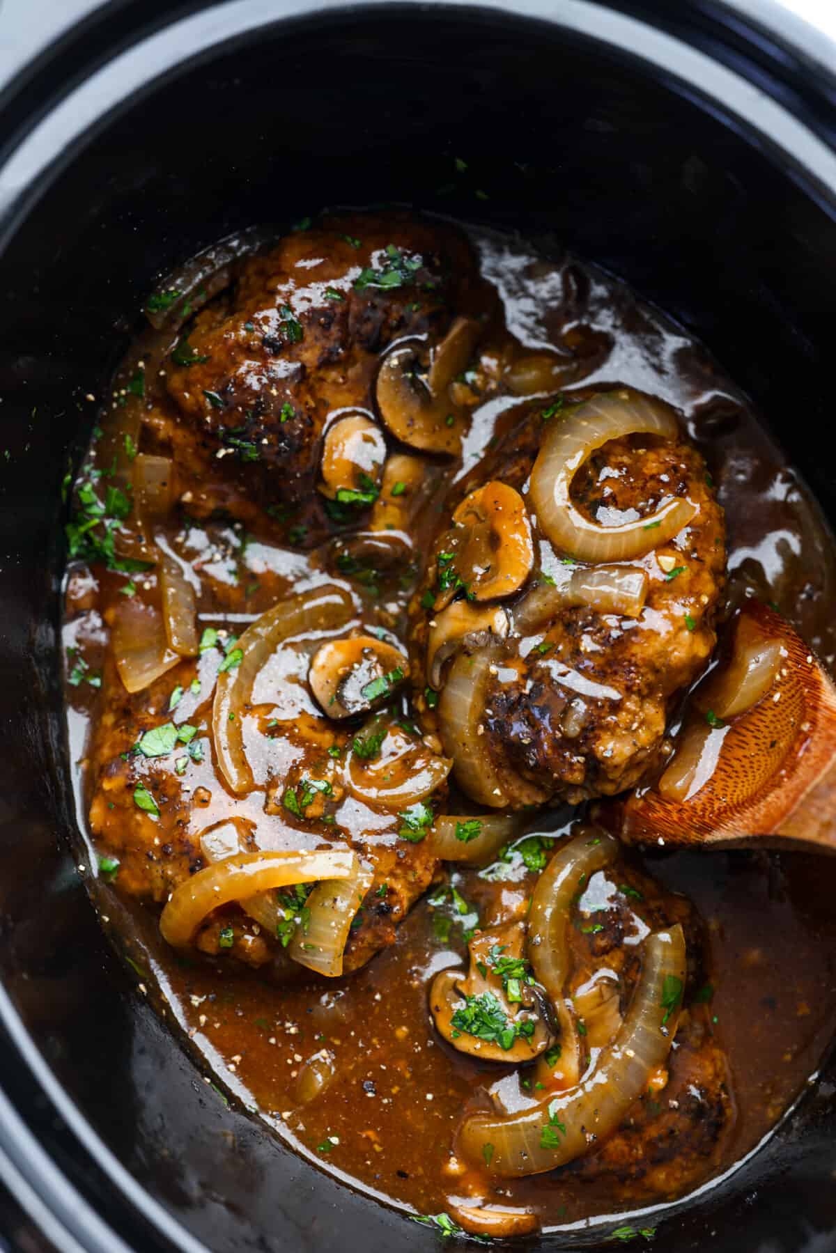 Salisbury Steaks in a slow cooker, covered with a mushroom and onion gravy.
