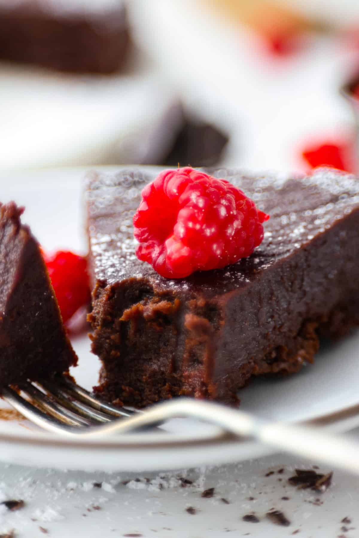 Flourless Chocolate Cake is an insanely rich and delicious chocolate dessert. Similar to the inside of a truffle, this gluten-free dessert will satisfy your sweet tooth with ease! A slice of cake with a bite taken out of it.