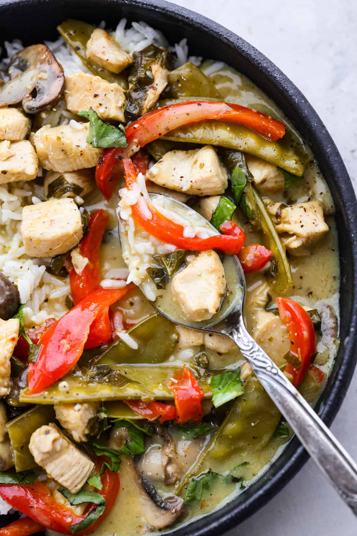 Homemade Thai Green Curry delivers a punch of flavor with its aromatic curry paste, creamy coconut milk, and tender chicken, making it a weeknight dinner you won't forget. A spoonful of chicken, vegetables, and rice on a metal spoon.