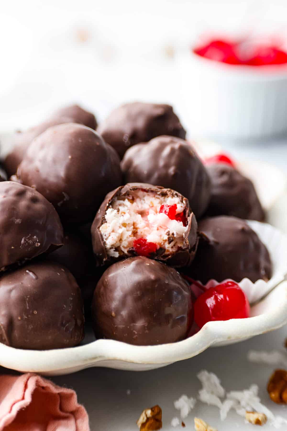 Chocolate-coated cherry truffles in a white scalloped serving dish.