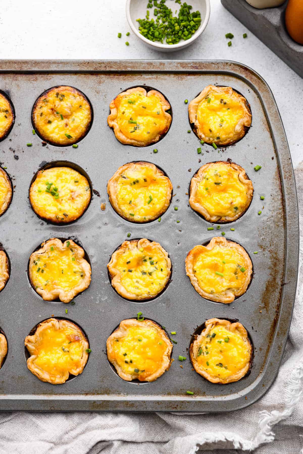 Cooked mini quiches in a muffin tin.