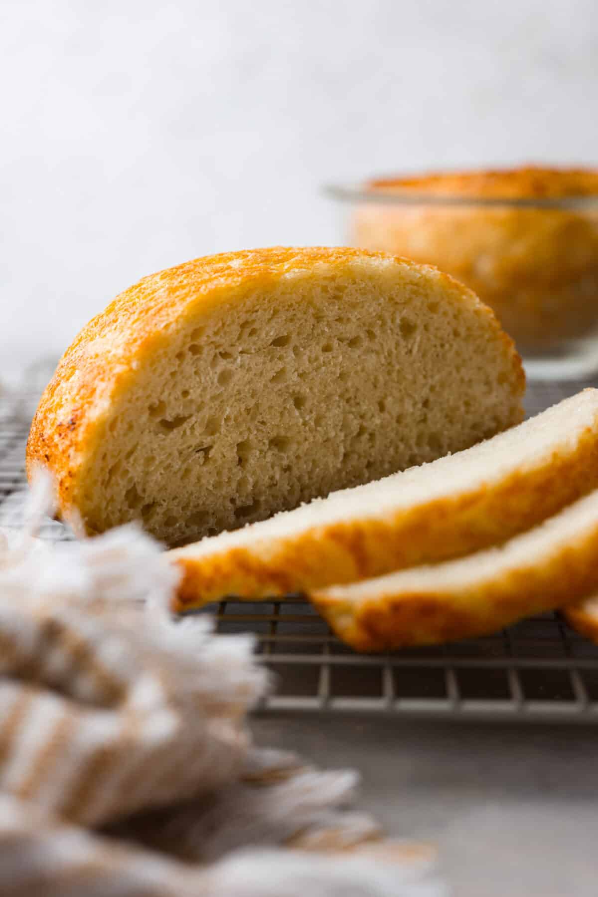 Close side view of sliced peasant bread on a cooling rack.