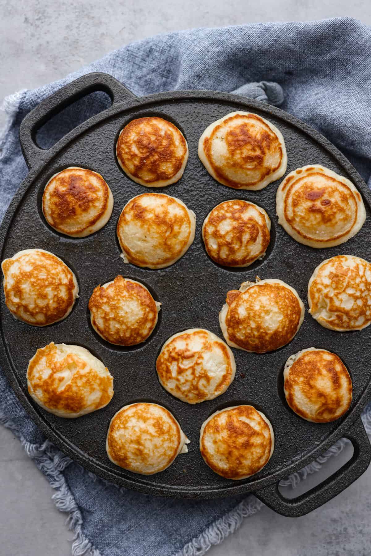 Top-down view of cooked poffertjes in a pan.