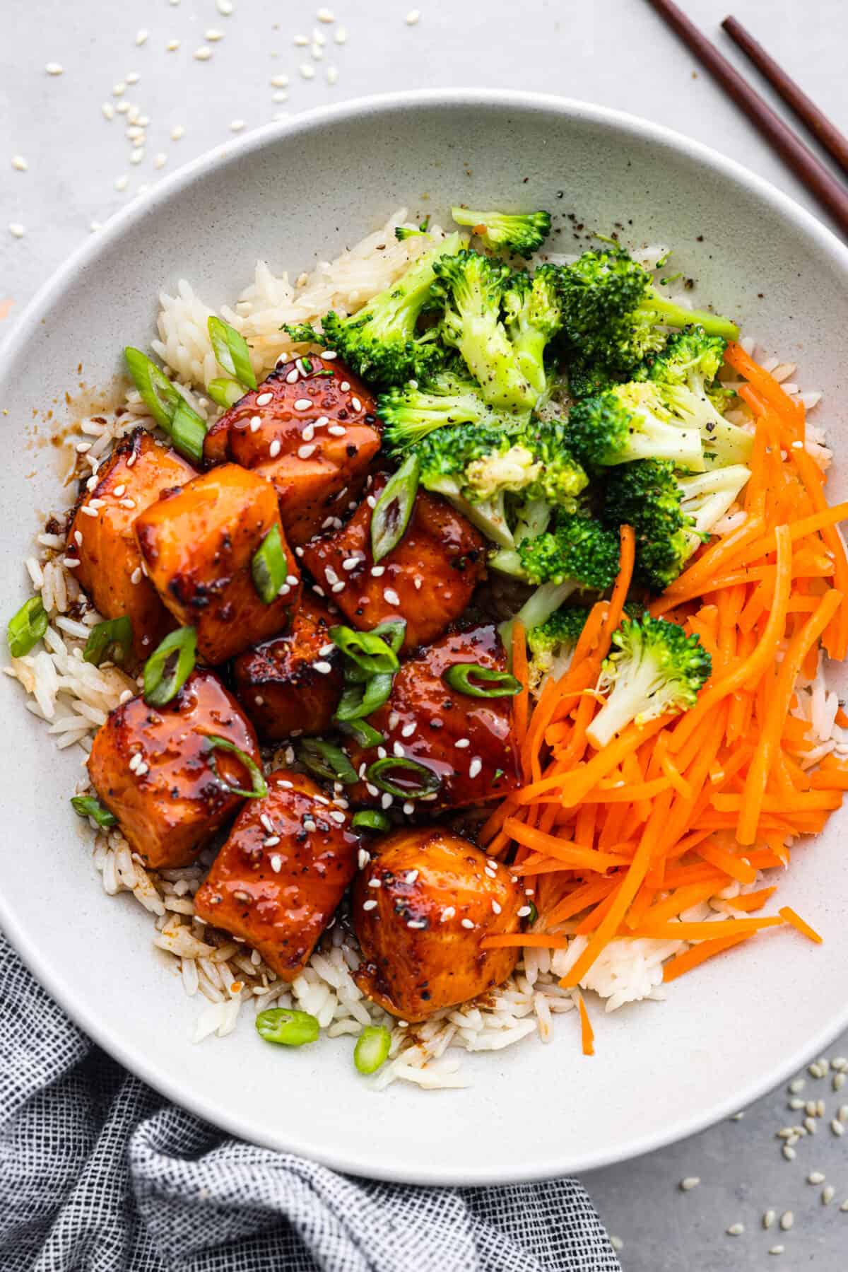 Say hello to your new favorite lunch: this honey-glazed salmon bowl made with juicy air fryer salmon bites, broccoli, and shredded carrots over white rice! White rice topped with salmon bites, broccoli, and shredded carrots.