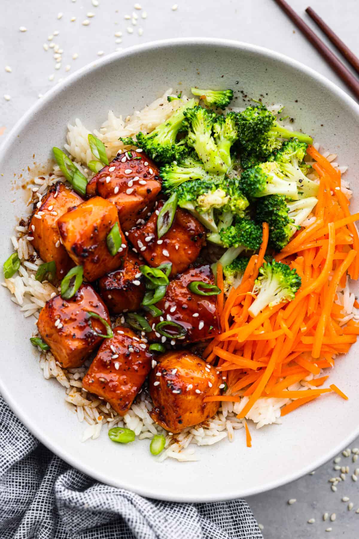 White rice topped with salmon bites, broccoli, and shredded carrots.