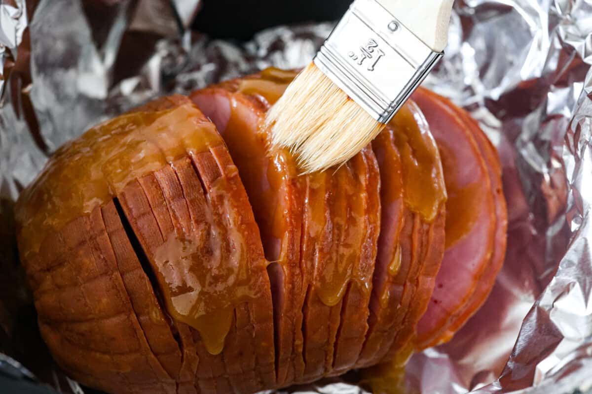 Brushing the air fryer ham with the brown sugar honey glaze.