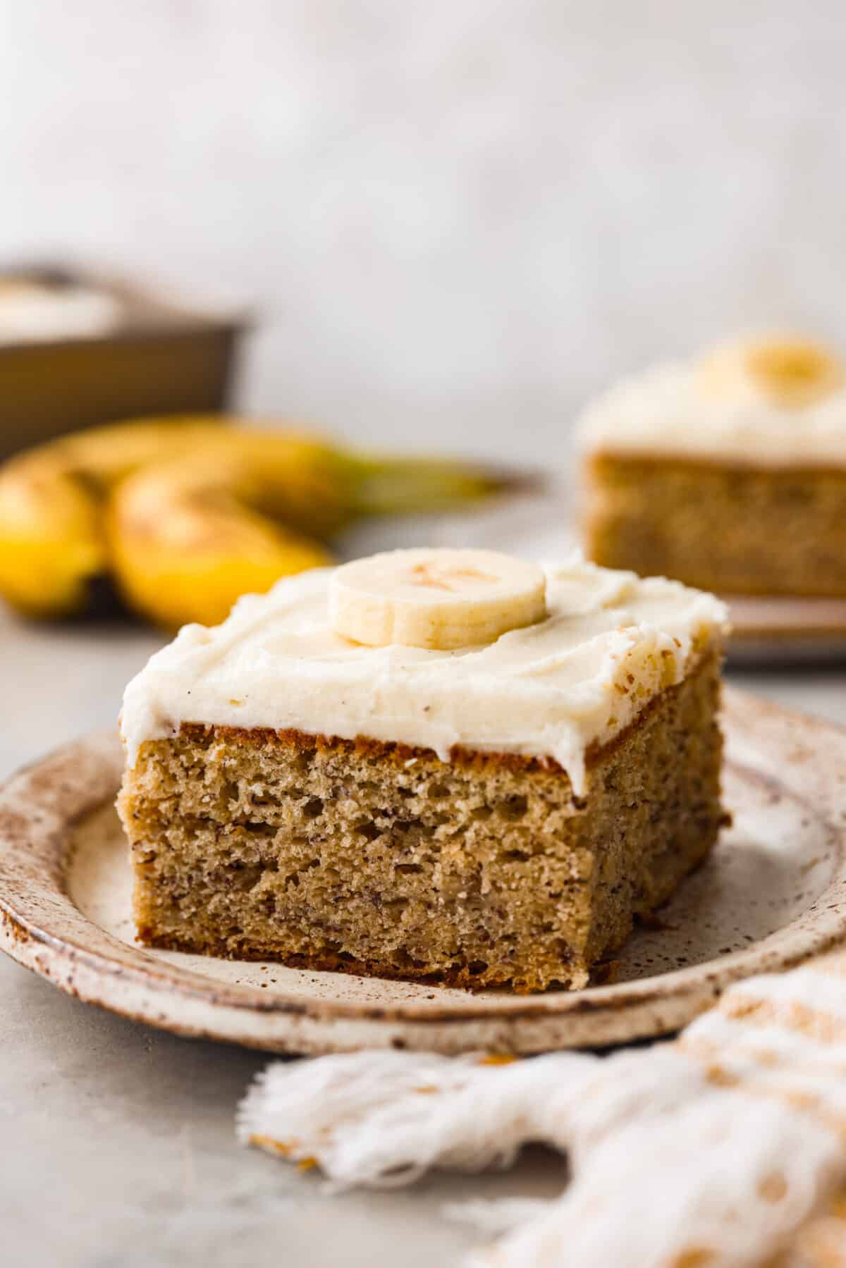 A slice of banana cake with cream cheese frosting.