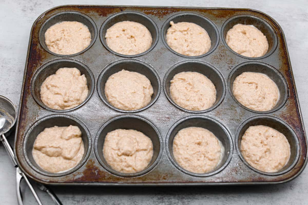 I see a batch of sweet and ultra-moist applesauce muffins in your future! They’re so delicious and made with all-natural sugars. The perfect breakfast, snack, dessert, you name it! The applesauce muffin batter being added to a muffin tin.
