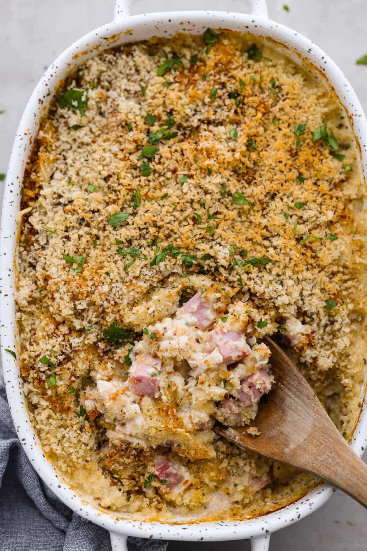Top-down view of chicken cordon bleu casserole with a scoop being taken out of it.