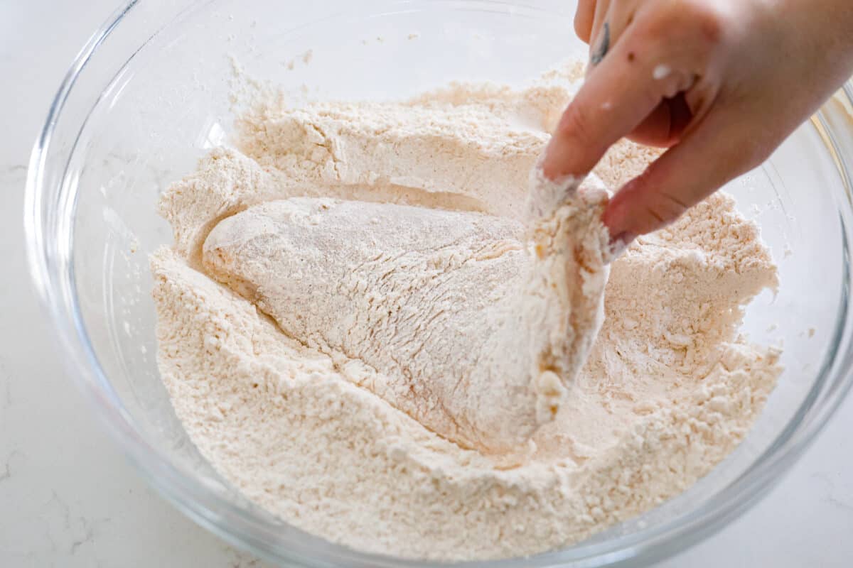 Coating the chicken in flour.