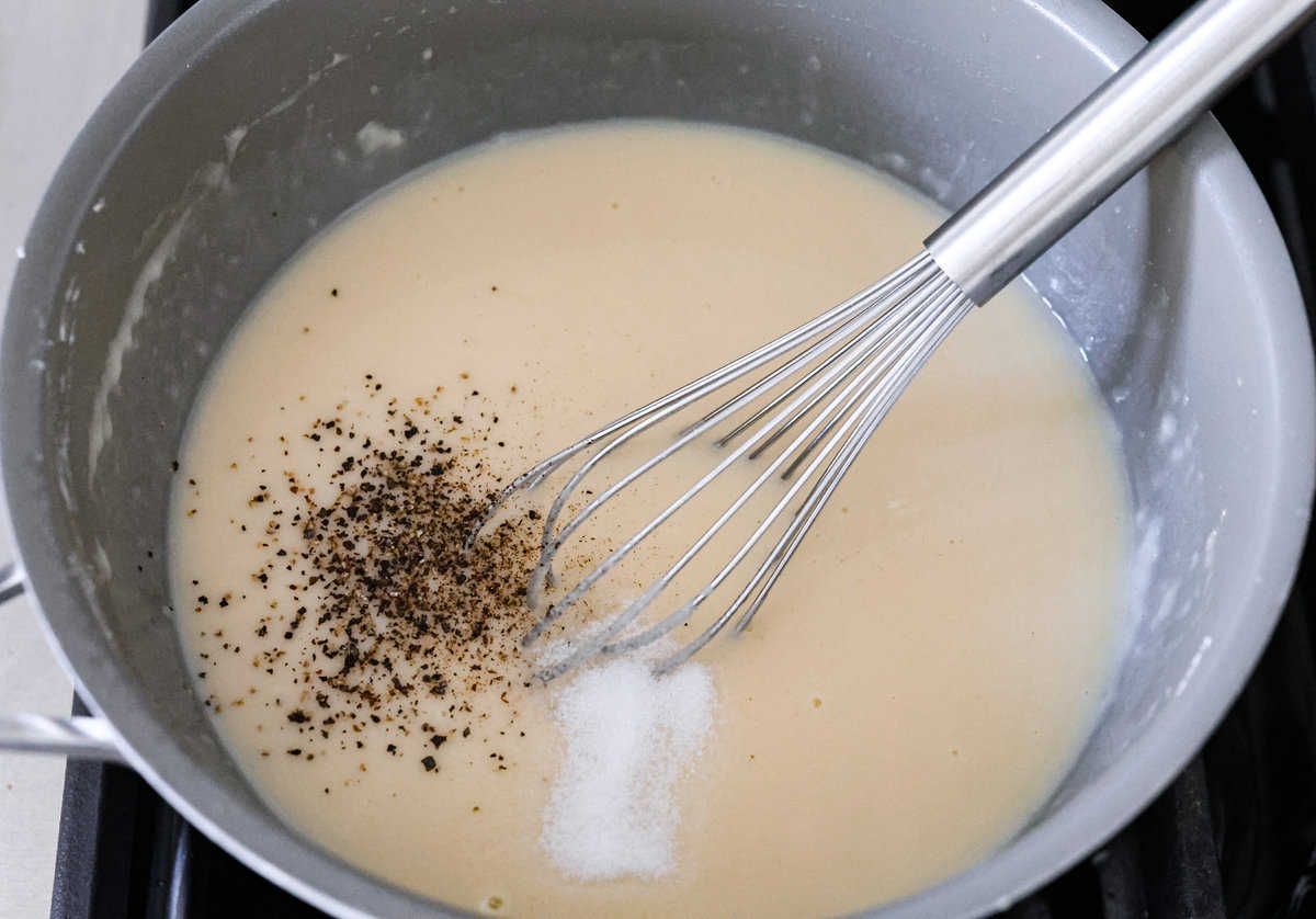 Bring all the best things about Southern cooking to your dinner table with this country fried chicken recipe! The result? Golden, crispy goodness smothered in savory homemade gravy. The gravy mixture being whisked together.