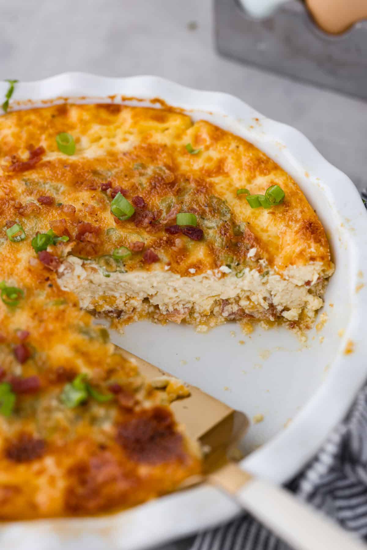 Quiche with a slice cut out of it.