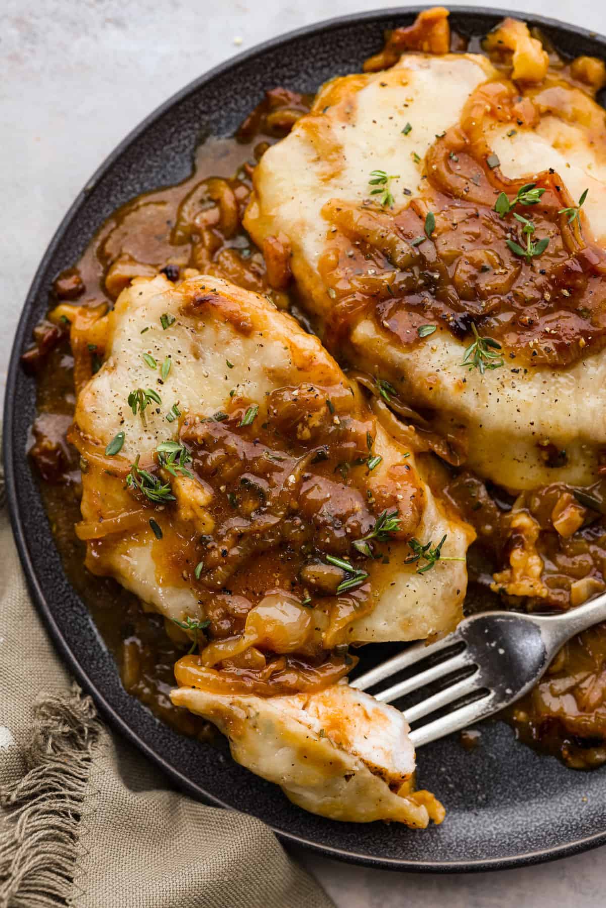 French Onion Pork Chops have all of the wonderful flavors of the classic soup in pork chop form! Caramelized onions and seared pork chops are joined with a savory sauce and two types of cheese for an amazing meal. Everything is cooked in one pan for a quick and easy weeknight dinner! Taking a bite of a pork chop