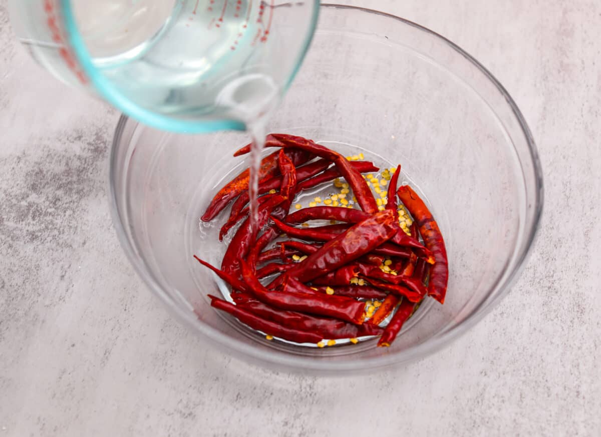 Covering dried peppers with water.